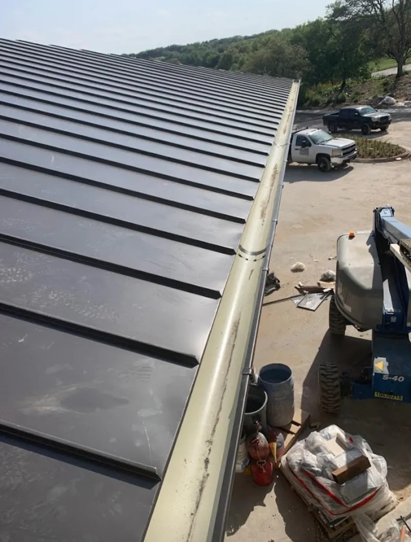 Standing seam panel and gutter detail on a metal roofing jobsite in Howell